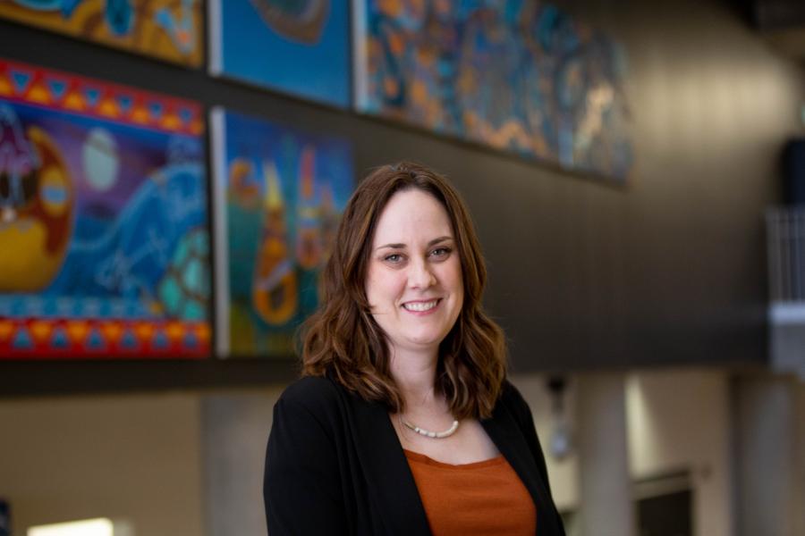 Headshot of Stephanie with artwork hanging on the walls in the background.