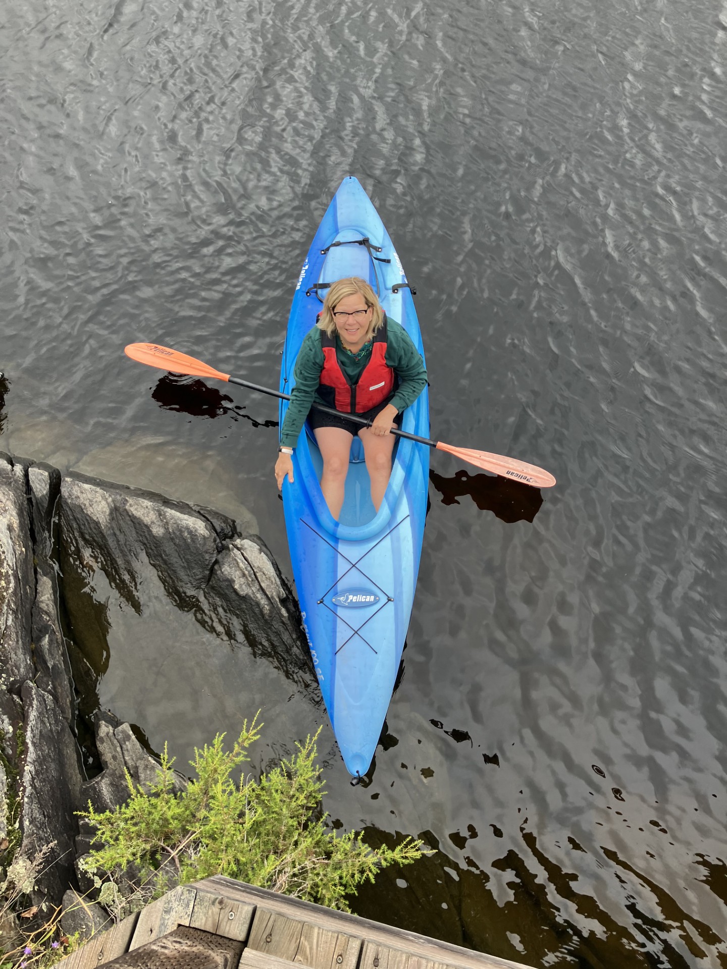 Image of Sarah sitting on a kayak in the water looking up to the camera