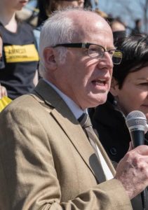 Photo of Alex Neve speaking into a microphone during a rally.